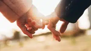 Closeup image of two lovers holding hands at sunset
